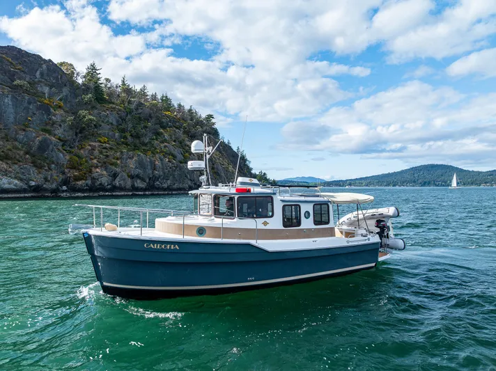 Caldonia Yacht Photos Pics 2013 Ranger Tugs R 29 boat cruising on scenic water with rocky shoreline and blue sky.