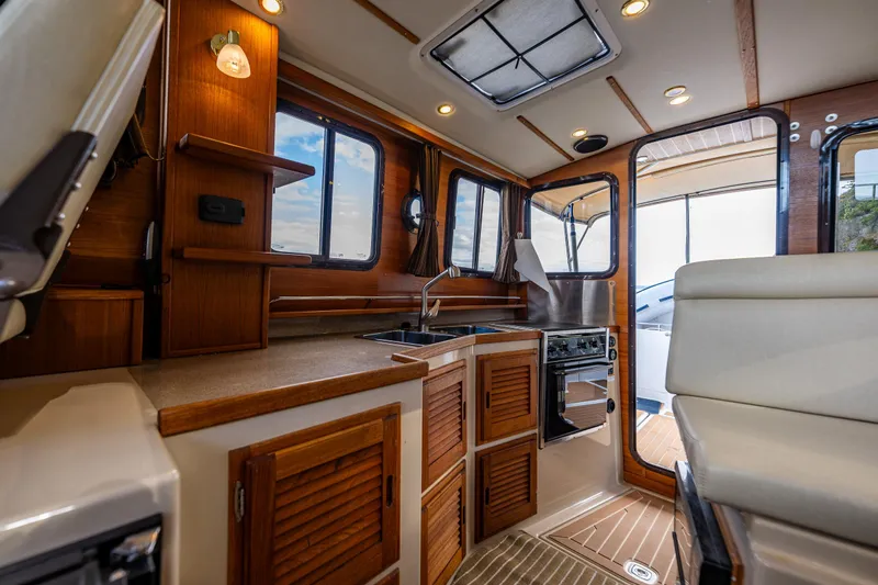 Caldonia Yacht Photos Pics Interior of 2013 Ranger Tugs R 29 boat, featuring a compact kitchen with wooden cabinetry.
