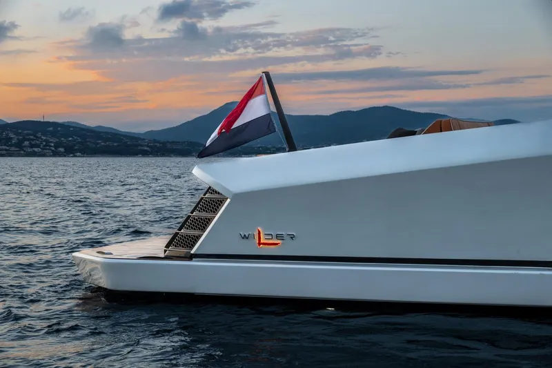  Yacht Photos Pics 2024 Wider Wilder 60 yacht at sunset on the water, featuring sleek design and flag.