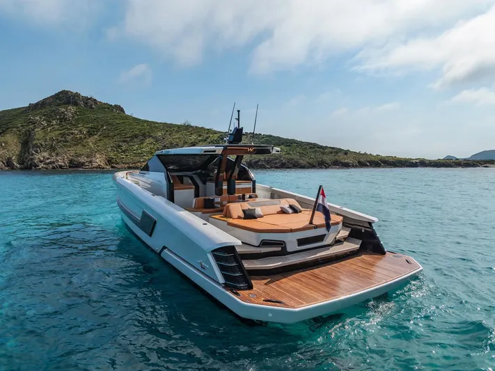  Yacht Photos Pics 2024 Wider Wilder 60 yacht cruising in clear blue waters near a scenic coastline.