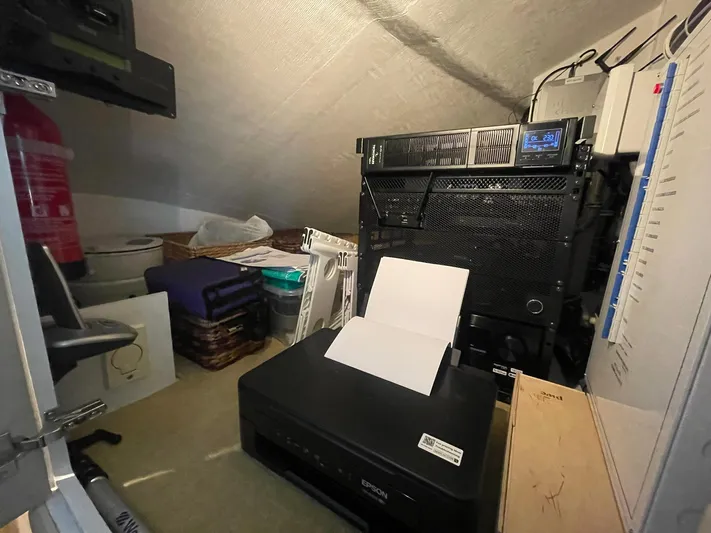 Caraibi Yacht Photos Pics Small storage room with office equipment, including a printer and server, aboard a 2013 Hatteras GT63.