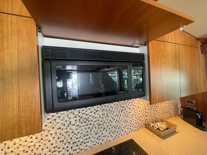 Caraibi Yacht Photos Pics Modern kitchen interior of 2013 Hatteras GT63 yacht with microwave and wooden cabinets.