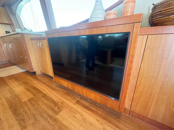 Caraibi Yacht Photos Pics 2013 Hatteras GT63 yacht interior with built-in TV, wooden cabinetry, and decorative items.