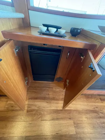 Caraibi Yacht Photos Pics 2013 Hatteras GT63 yacht interior with open wooden cabinet and small refrigerator.