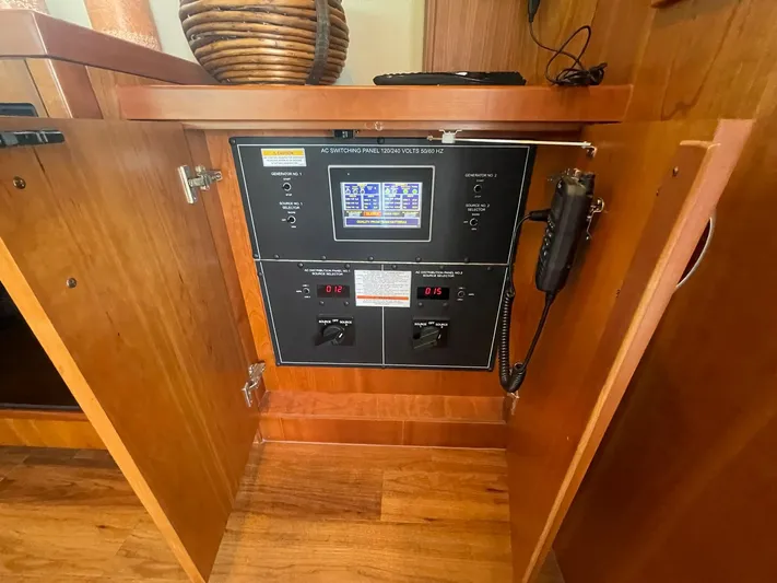 Caraibi Yacht Photos Pics Electrical control panel inside a 2013 Hatteras GT63 yacht, featuring wood cabinetry.