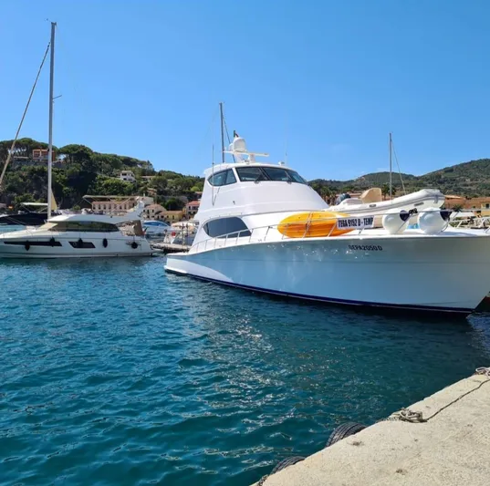 Caraibi Yacht Photos Pics 2013 Hatteras GT63 yacht docked in a scenic marina with clear blue water.