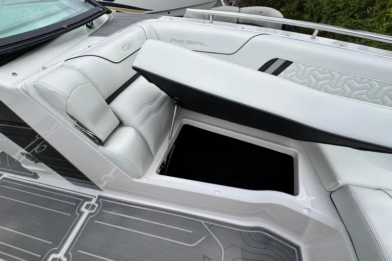  Yacht Photos Pics 2024 Regal LX9 boat interior with open storage compartment and white cushioned seating.