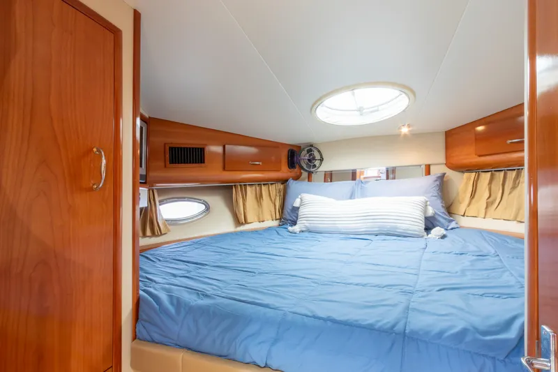  Yacht Photos Pics Luxurious bedroom interior of 2005 Carver 390 MY yacht with blue bedding and wood accents.