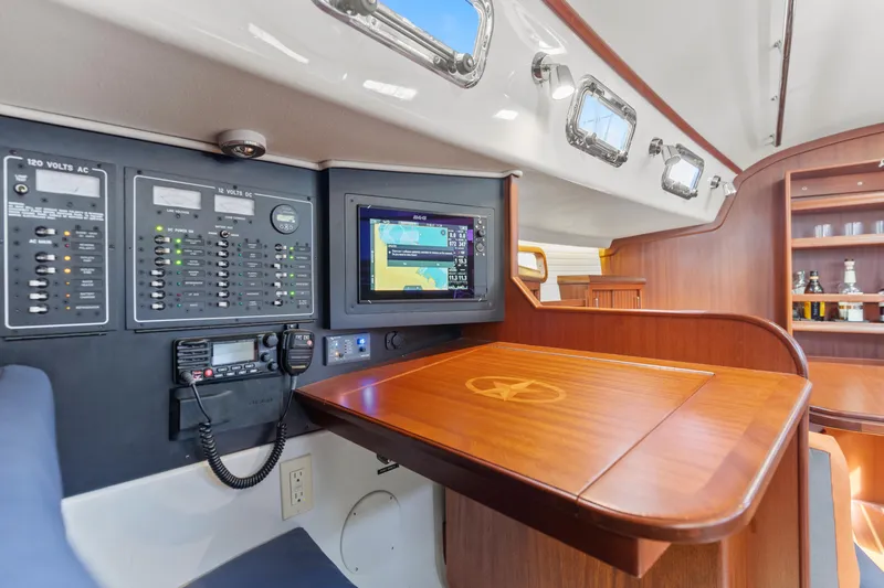 Resolute Yacht Photos Pics Navigation station inside 2015 Blue Jacket 40 sailboat with control panels and wooden desk.