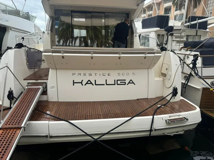  Yacht Photos Pics 2011 Prestige 500 S yacht docked, rear view with wooden deck and "KALUGA" name.