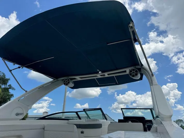  Yacht Photos Pics 2022 Sea Ray SDX 290 Outboard boat with blue canopy under a cloudy sky.
