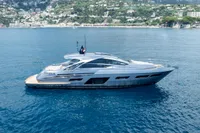 2024 Pershing 7X yacht cruising on clear blue waters near a scenic coastal town.