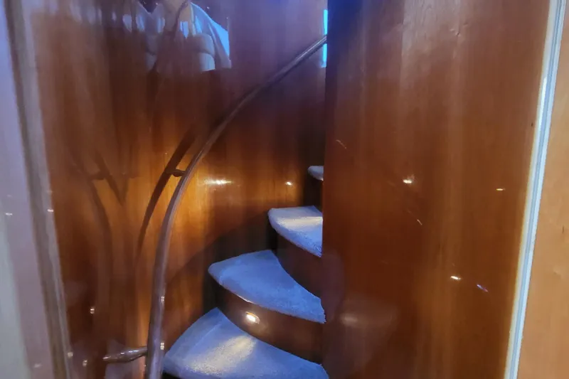  Yacht Photos Pics Curved wooden staircase inside 2000 Horizon 74 Motor Yacht, featuring elegant design and soft lighting.