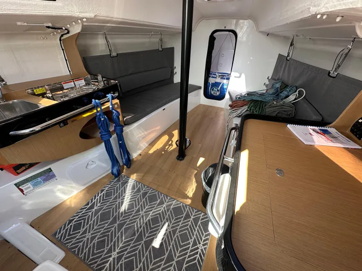 Rebel Yacht Photos Pics Interior of 2021 Jeanneau Sun Fast 3300 sailboat, featuring seating, table, and nautical equipment.