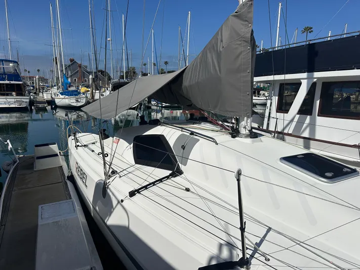 Rebel Yacht Photos Pics 2021 Jeanneau Sun Fast 3300 sailboat docked in marina, sails partially raised.