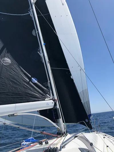 Rebel Yacht Photos Pics 2021 Jeanneau SUNFAST 3300 sailboat with black sails on open water.