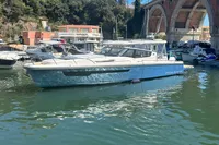 2023 Nimbus W11 boat docked near a scenic bridge and lush greenery.