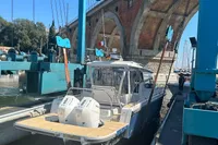2023 Nimbus W11 boat being lifted near a bridge at a marina.