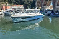 2023 Nimbus W11 boat docked near a bridge in a sunny marina.