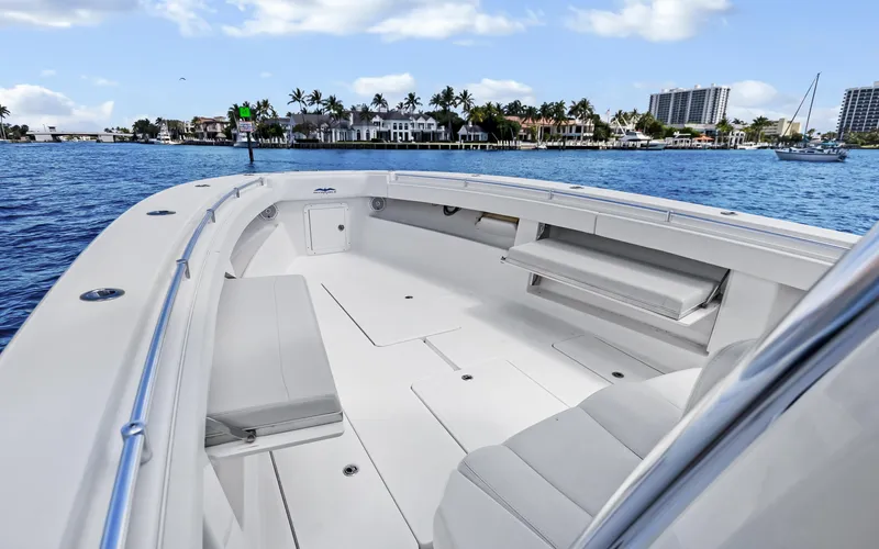  Yacht Photos Pics 2016 Invincible 39 boat with spacious deck, cruising near waterfront homes under a blue sky.
