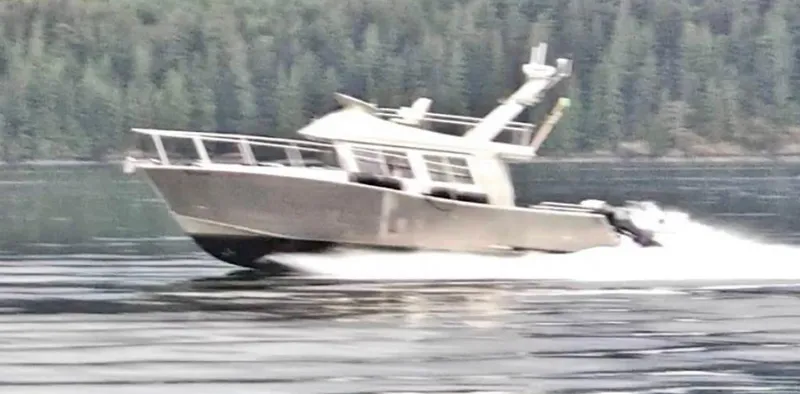  Yacht Photos Pics 2007 Coastal Craft 36 Cruiser speeding on a serene lake with forest backdrop.