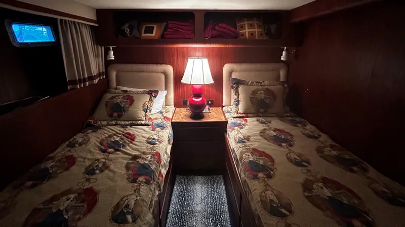  Yacht Photos Pics Cozy twin bedroom on 1987 Hatteras 58 Motor Yacht with nautical-themed bedding and warm lighting.