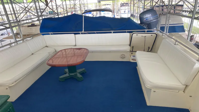  Yacht Photos Pics 1987 Hatteras 58 Motor Yacht interior with white seating and wooden table on blue carpet.