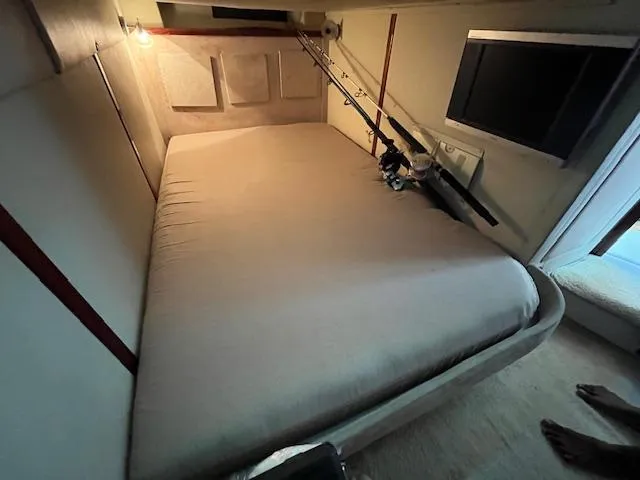 Alacrity Yacht Photos Pics 2008 Doral Mediterra cabin interior with bed, fishing rods, and TV.