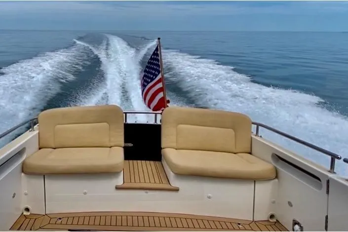 By The Way Yacht Photos Pics 2015 MJM 36z Express boat cruising with American flag, teak deck, and cushioned seating.