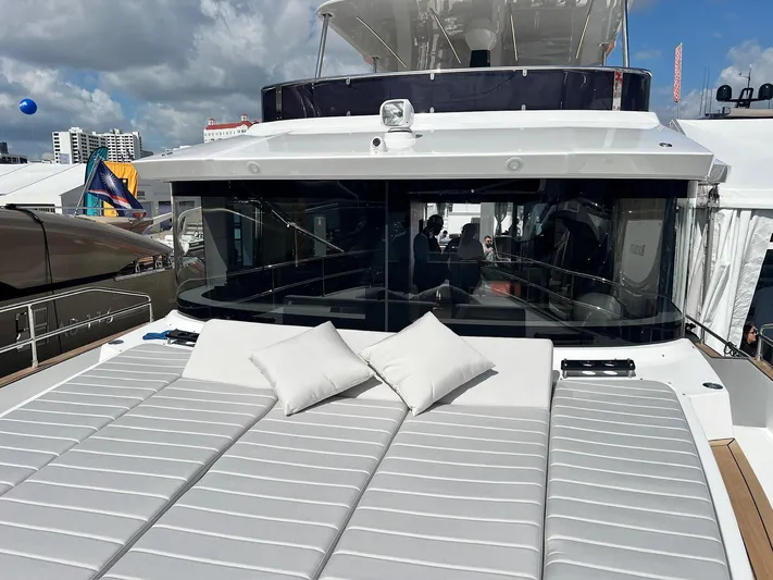  Yacht Photos Pics 2024 Sirena 48 Flybridge yacht with sunbathing area and cushions, docked at a marina.