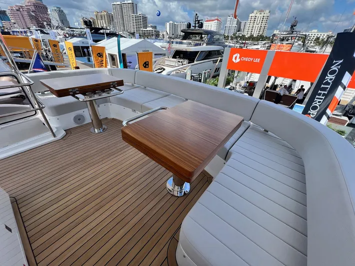  Yacht Photos Pics Luxurious seating area on 2024 Sirena 48 Flybridge yacht, featuring wooden tables and cityscape backdrop.