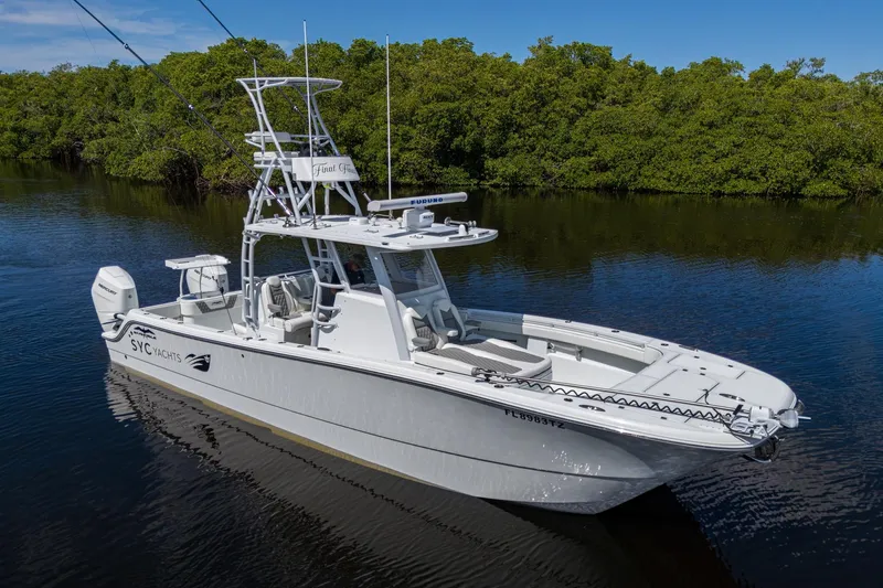 Final/final Yacht Photos Pics 2025 Invincible 33 Catamaran on calm water, surrounded by lush greenery.