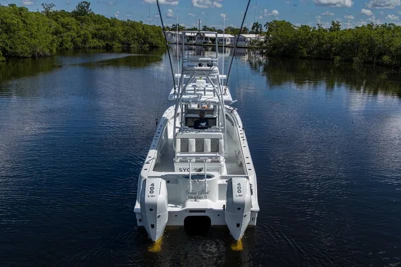 Final/final Yacht Photos Pics 2025 Invincible 33 Catamaran on calm water, surrounded by lush greenery.