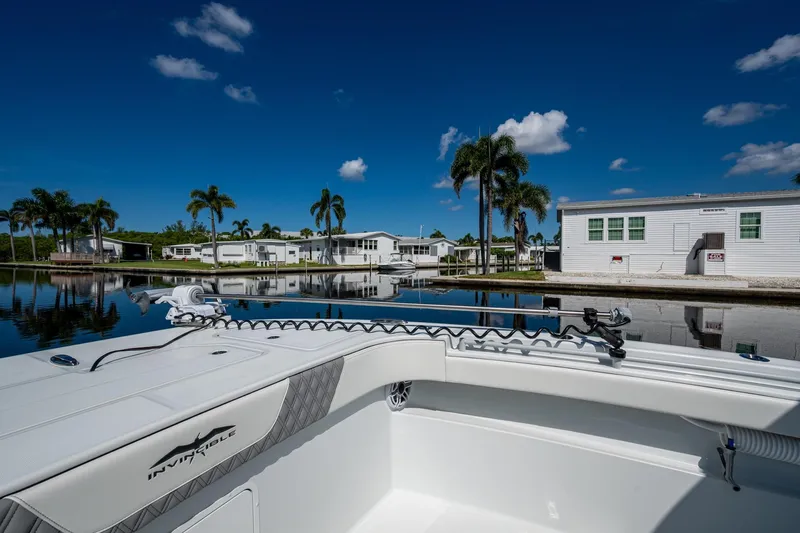 Final/final Yacht Photos Pics 2025 Invincible 33 Catamaran docked by palm trees and waterfront homes under clear blue sky.