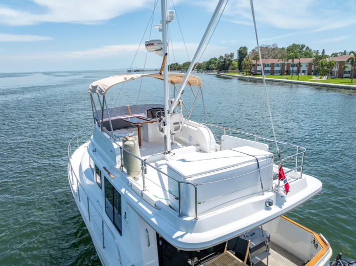 Good Timimg Yacht Photos Pics 2015 Beneteau Swift Trawler 34 on serene water, showcasing upper deck and scenic shoreline.