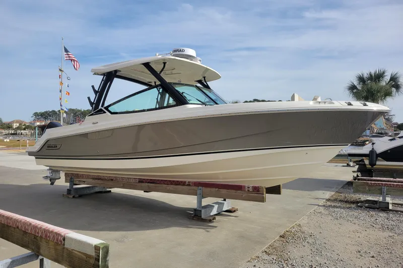  Yacht Photos Pics 2023 Boston Whaler 280 Vantage boat displayed on a dock with flags and palm trees.