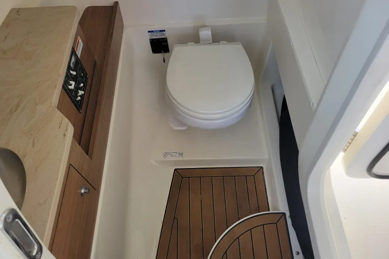  Yacht Photos Pics 2023 Boston Whaler 280 Vantage boat bathroom with toilet and wooden flooring.