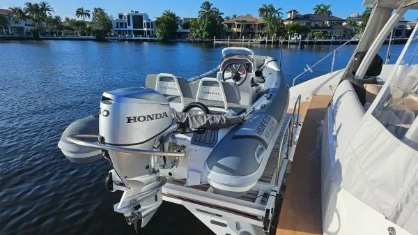 Sunlove Yacht Photos Pics 2024 Lagoon SIXTY 7 yacht with a Honda-powered tender on a sunny waterfront.