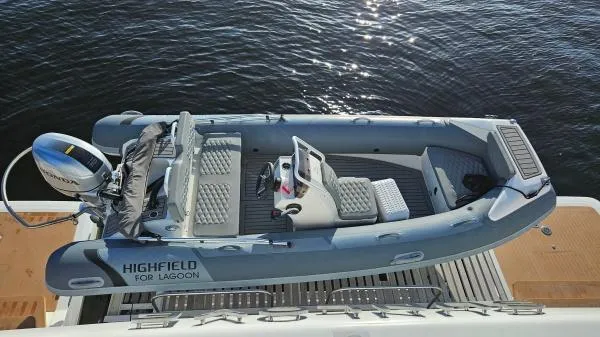 Sunlove Yacht Photos Pics 2024 Lagoon SIXTY 7 yacht with Highfield tender on deck, docked by the water.