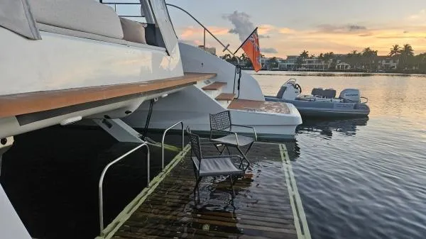 Sunlove Yacht Photos Pics 2024 Lagoon SIXTY 7 yacht with deck chairs, docked at sunset.