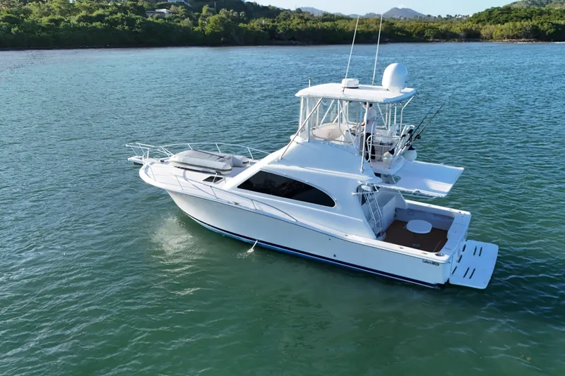  Yacht Photos Pics 2005 Luhrs 38 Convertible yacht on calm water, surrounded by lush greenery.