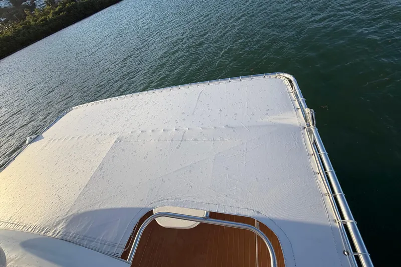  Yacht Photos Pics 2005 Luhrs 38 Convertible boat deck with white cover, overlooking calm water.