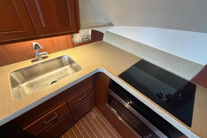  Yacht Photos Pics 2005 Luhrs 38 Convertible yacht kitchen with sink, stovetop, and wooden cabinetry.
