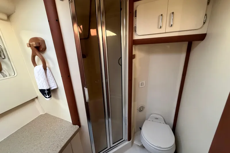  Yacht Photos Pics 2005 Luhrs 38 Convertible yacht bathroom with shower, toilet, and nautical-themed towel.