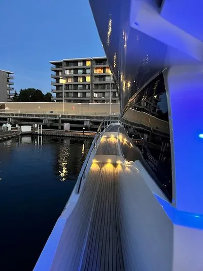  Yacht Photos Pics Prestige 750 yacht docked at marina, evening lights reflecting on water.