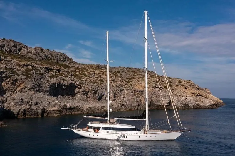  Yacht Photos Pics Custom 2012 Motorsailor yacht anchored near rocky coastline under clear blue sky.