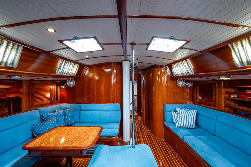 Ghost Yacht Photos Pics Luxurious interior of 2000 Hinckley Sou'wester Stoway Sloop with blue seating and wooden finishes.