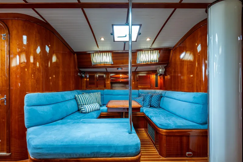 Ghost Yacht Photos Pics Luxurious interior of 2000 Hinckley Sou'wester Stoway Sloop with blue seating and wooden finish.