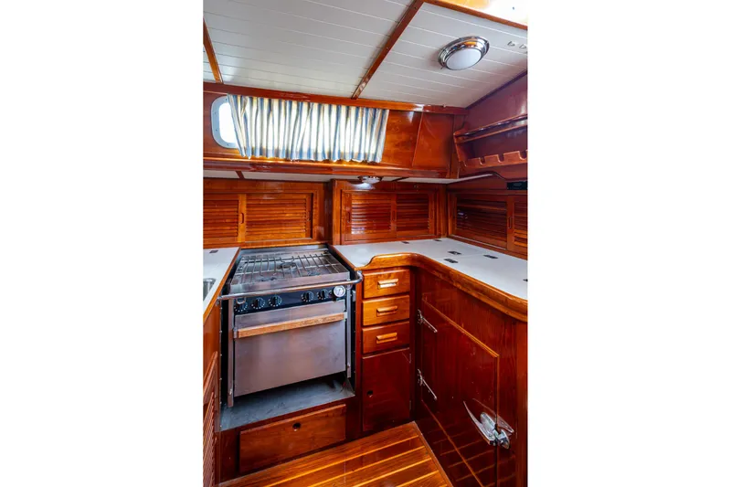 Ghost Yacht Photos Pics Hinckley Sou'wester Stoway Sloop 2000 interior with wooden cabinetry and stove.
