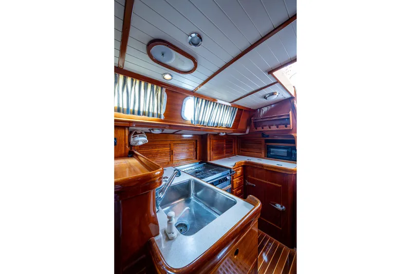 Ghost Yacht Photos Pics Hinckley Sou'wester Stoway Sloop 2000 interior kitchen with wood finish and modern appliances.